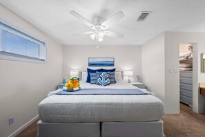 A bedroom with a bed, a ceiling fan, a window with blinds, a nightstand, a lamp, and a wall-mounted TV. - Sugar Beach 323 (Orange Beach)