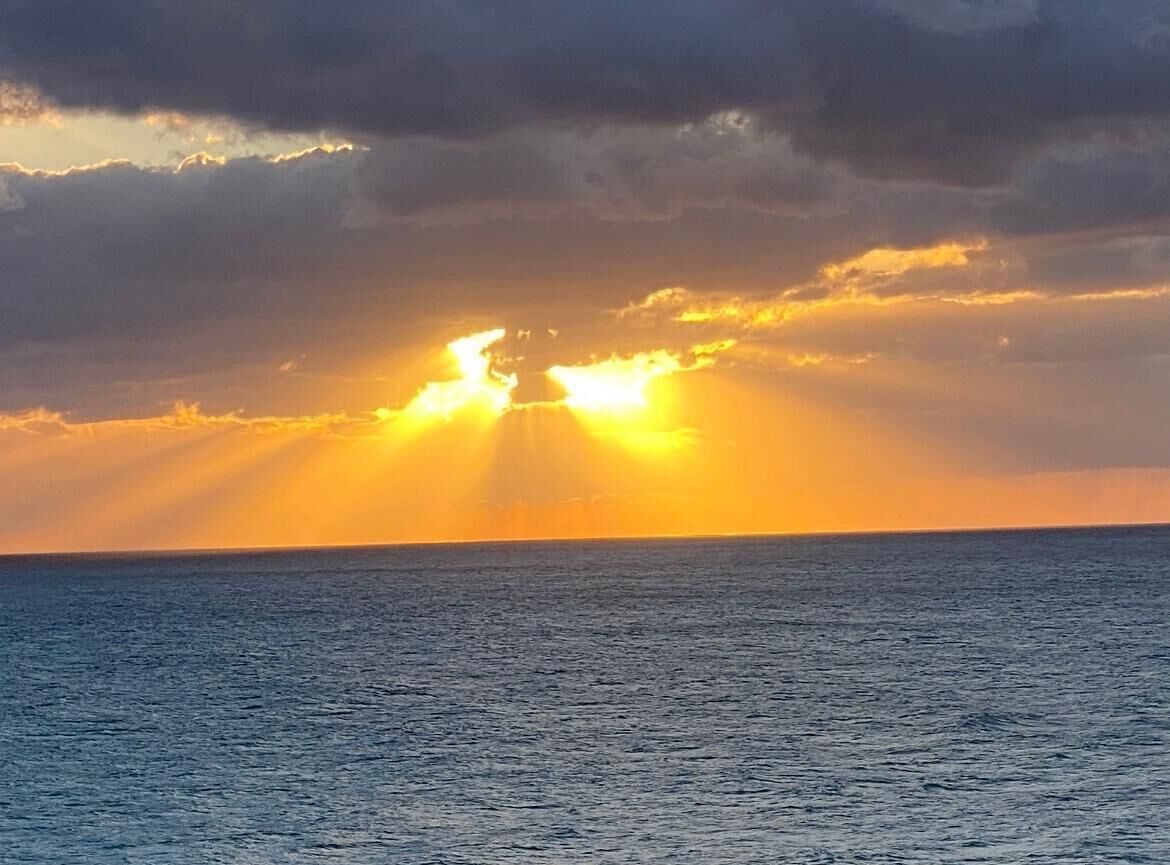 Atardecer sobre un mar tranquilo con nubes.