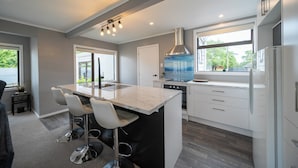 A modern kitchen with a central island, white cabinetry, and a large window.