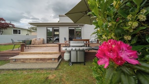 A backyard with a barbecue grill, outdoor seating, and a covered patio area.