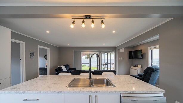 A modern kitchen with a marble countertop, stainless steel sink, and built-in dishwasher.
