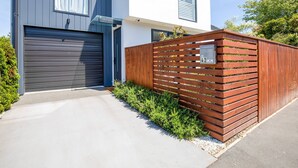 Una casa moderna de dos pisos con garaje, cerca de una valla de madera y un buzón.
