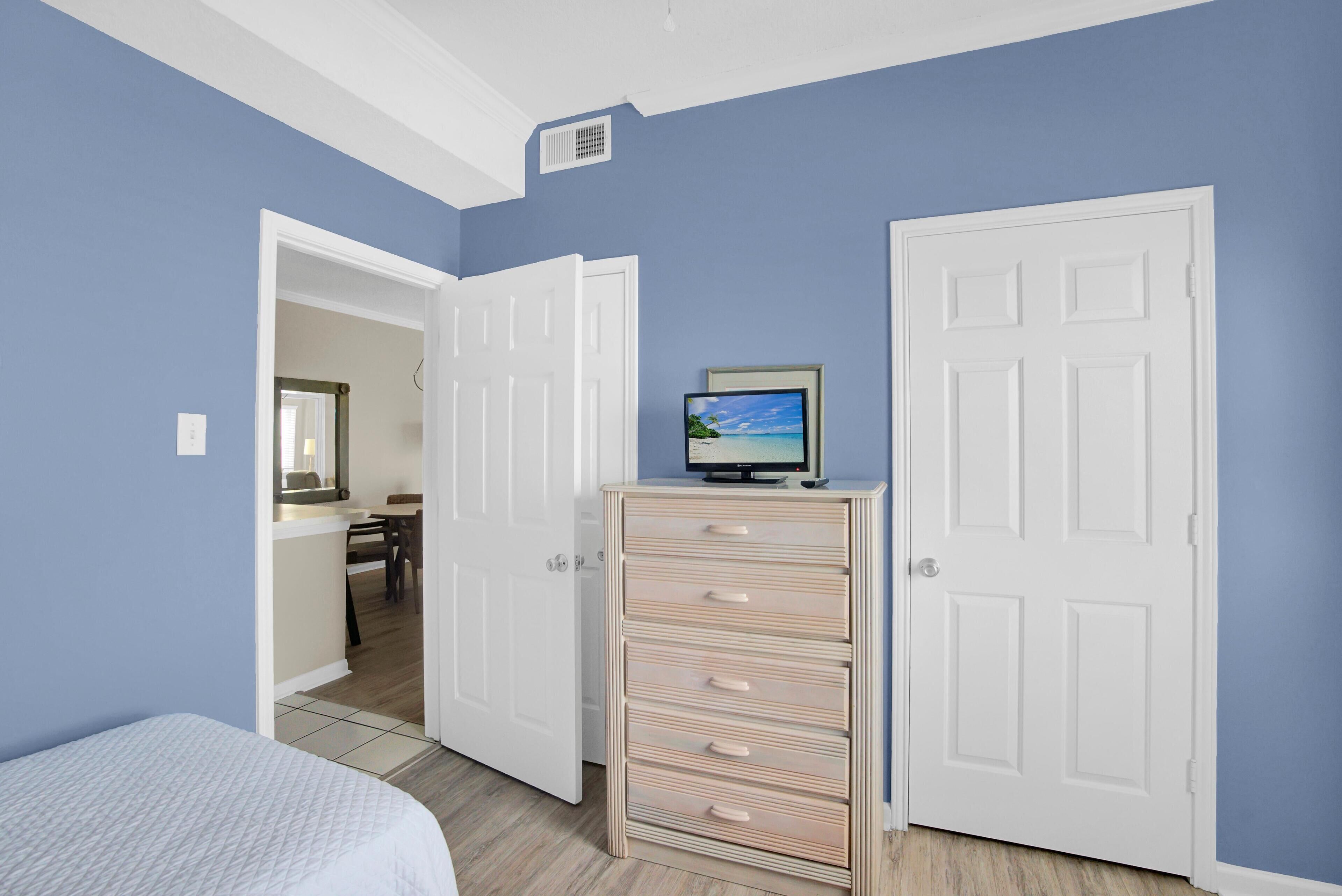 Une chambre à coucher avec un lit, une commode et deux portes blanches.
