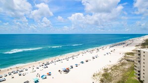 Ein Strand mit klarem Himmel, sandigem Ufer und einem Gebäude direkt am Strand.