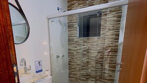 Un baño con inodoro, lavamanos y cabina de ducha de vidrio.