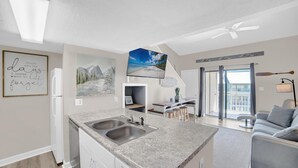 Een moderne keuken met granieten aanrecht, een dubbele spoelbak en een eethoek met een barstoel.