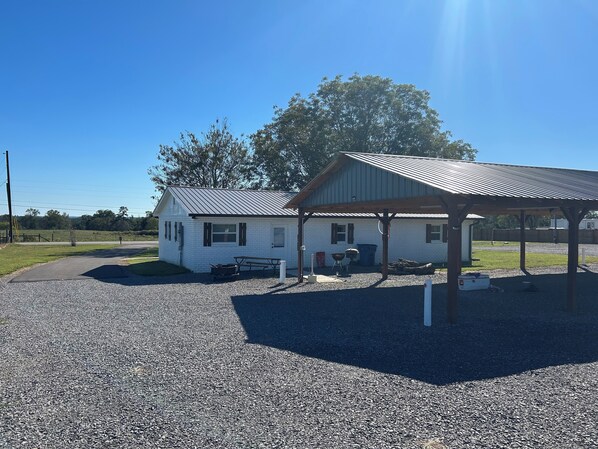 A white building with a metal roof and a covered outdoor area with a picnic table.