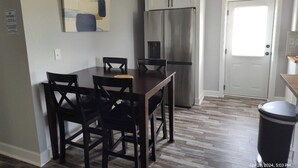 A dining area with a dark wooden table and chairs, a stainless steel refrigerator, and a white door. - Close to Lake G’VILLE 3-BR house with AC, BOAT BARN-24’x48’, WiFi in Albertville (Albertville)