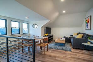 Un salon moderne comprenant un coin repas, de grandes fenêtres, un téléviseur à écran plat et un canapé confortable.
