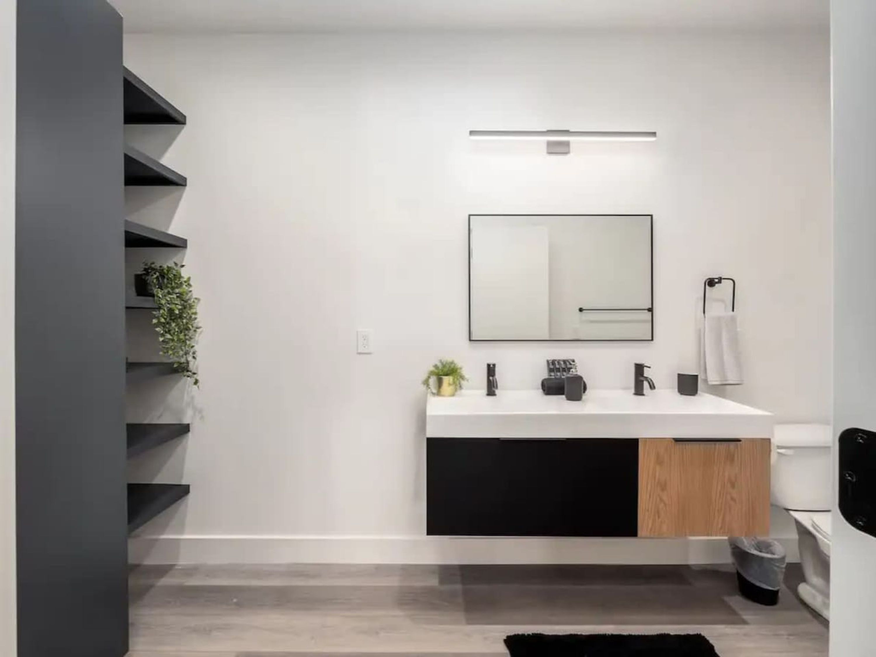A modern bathroom with a white sink, black cabinet, and a mirror.
