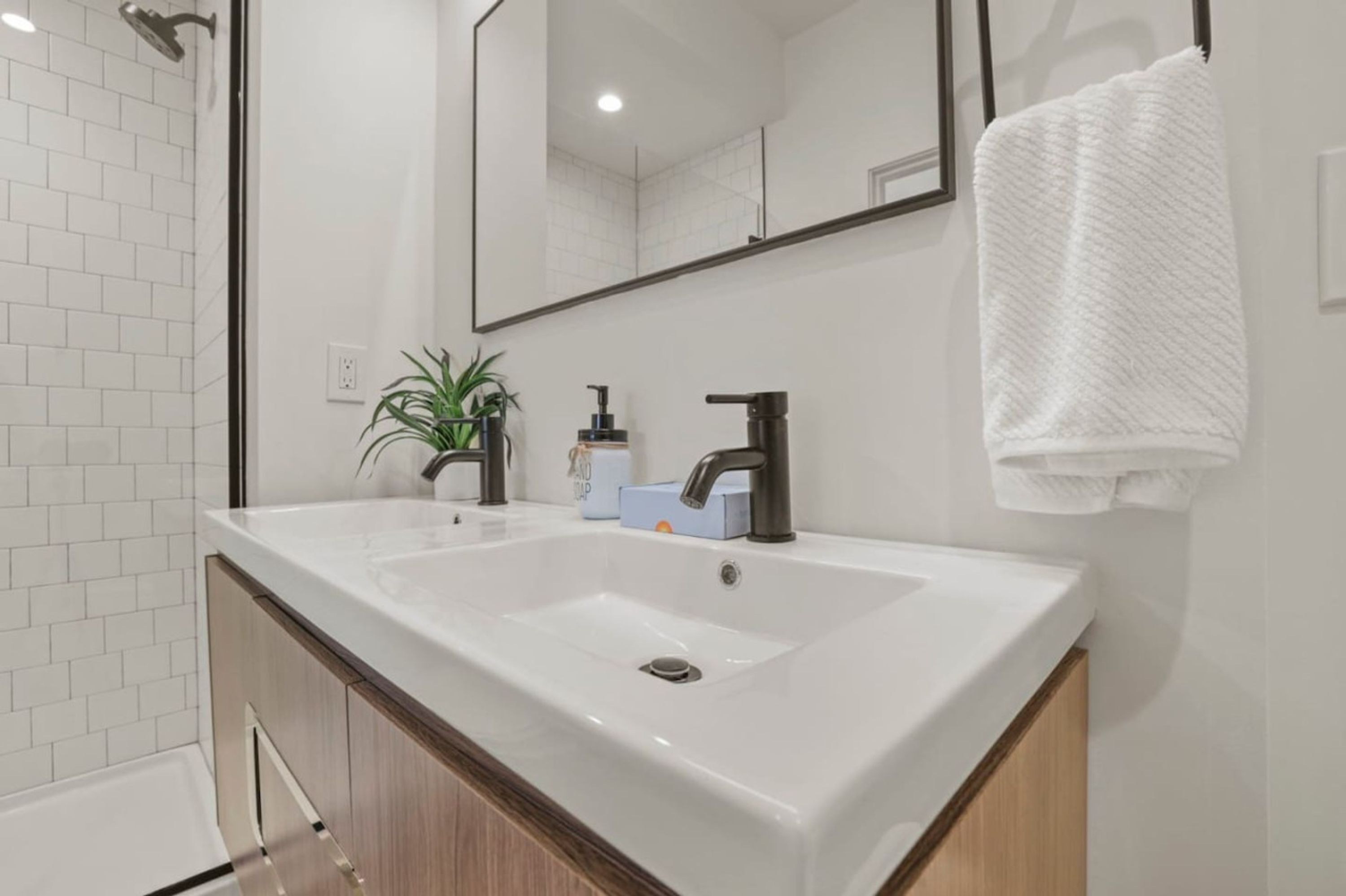 A modern bathroom with a large white sink, a mirror, and a towel hanging on the wall.