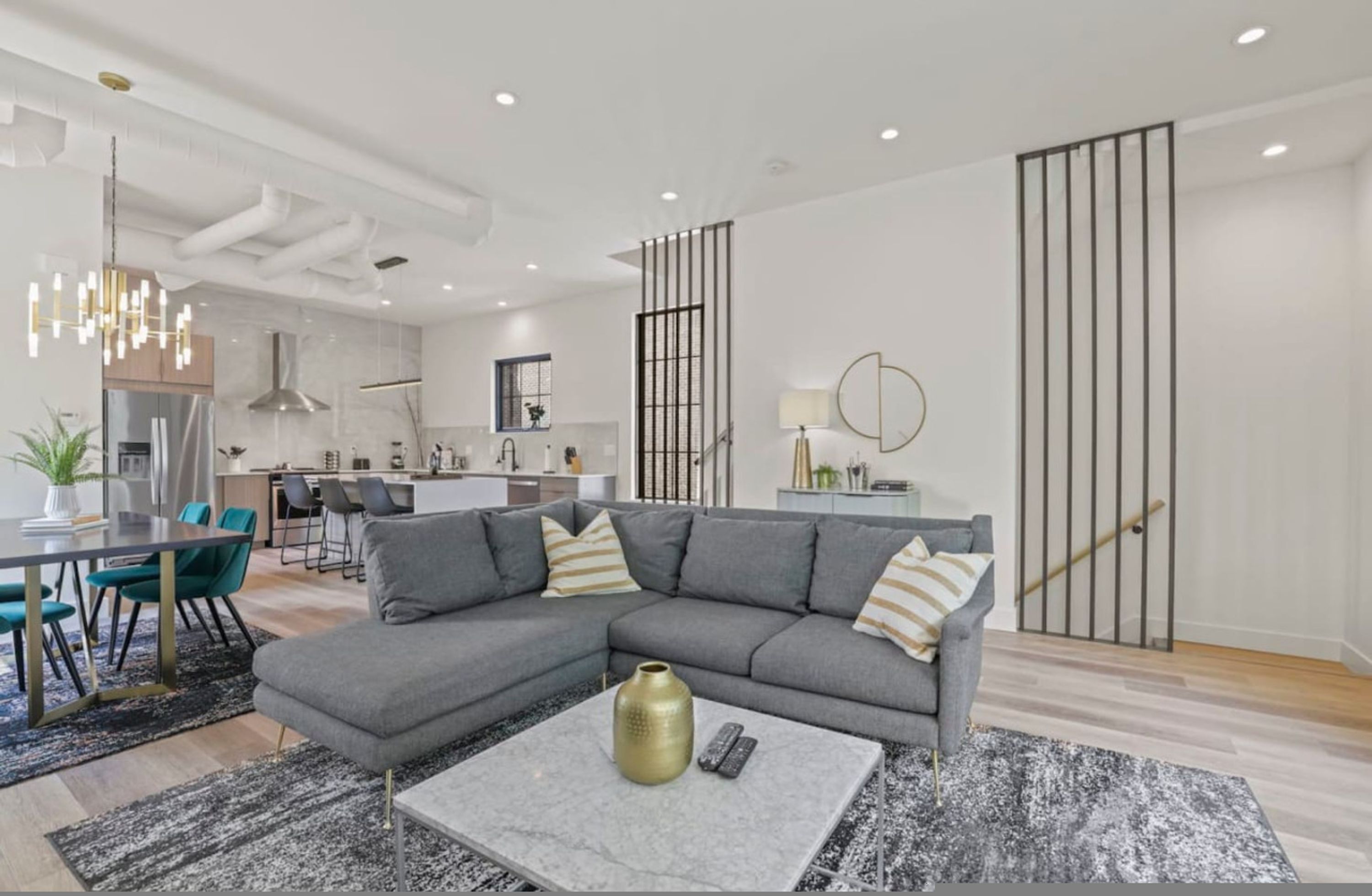 A modern living room with a grey sectional sofa, a coffee table, and a dining area with a table and chairs.