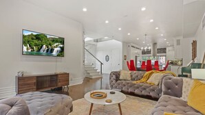 A spacious living room with a large flat-screen TV, a comfortable sofa set, and a staircase leading to an upper level. - Franklin Manor-columbus Downtown Luxury Estate (Columbus)