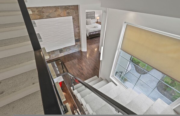 A modern interior with a staircase, a bedroom with a bed and nightstand, and a view of the outdoors through a window. - Franklin Manor-columbus Downtown Luxury Estate (Columbus)