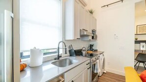 A compact kitchen with white cabinets, a stainless steel sink, and a built-in oven. - The Loft Columbus Center 3 (Columbus)