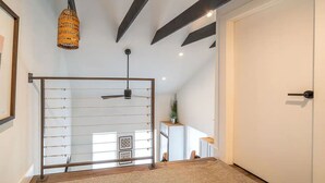 A modern bedroom with a sloped ceiling, a metal gate, a ceiling fan, and a hanging light fixture. - The Loft Columbus Center 3 (Columbus)