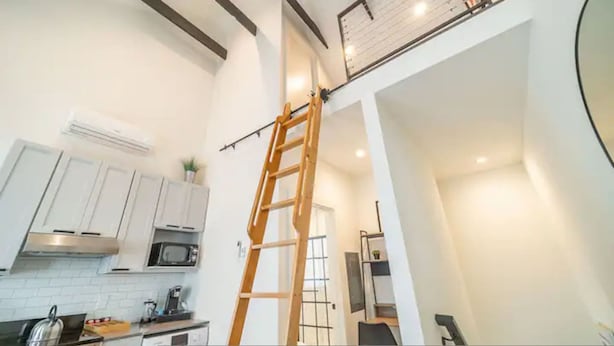 A kitchen with white cabinets, a wooden ladder, a microwave, and a coffee machine. - The Loft Columbus Center 3 (Columbus)
