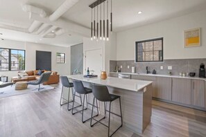 A modern kitchen with a central island, bar stools, and a large window. - Work Of Art -3 Bedroom Elegant Townhome-columbus (Columbus)