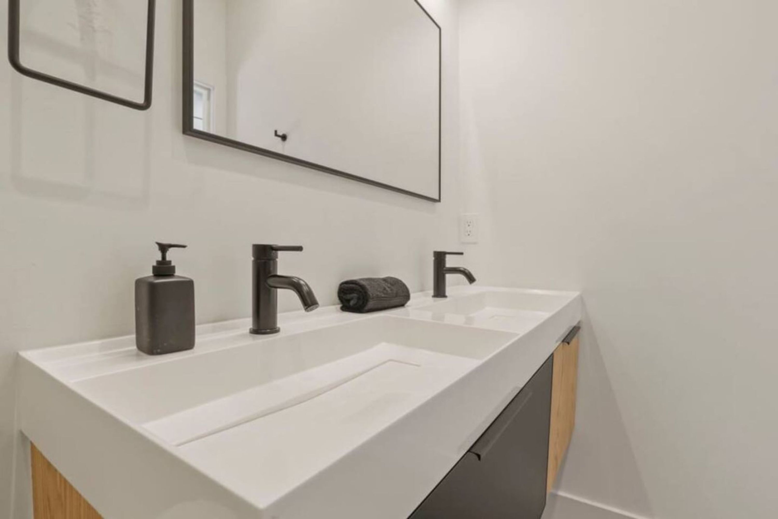 A modern bathroom with a white countertop, two sinks, and a large mirror.