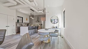 Une cuisine moderne dotée d’un îlot central, de luminaires suspendus et d’une table de salle à manger ronde avec des chaises.