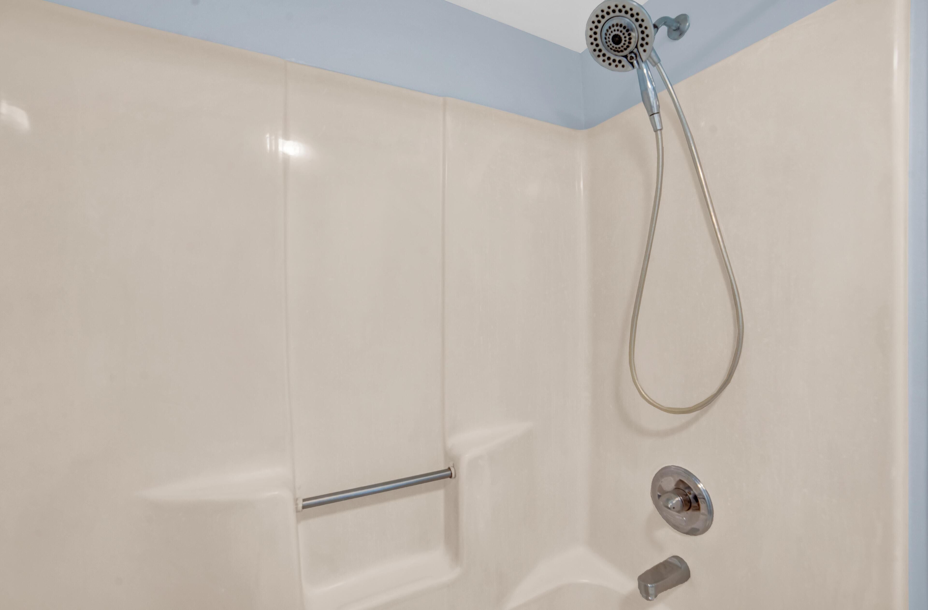 A shower with a handheld showerhead and a wall-mounted control valve.