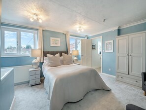 Une chambre à coucher comprenant un lit, des tables de chevet, un radiateur et une armoire.