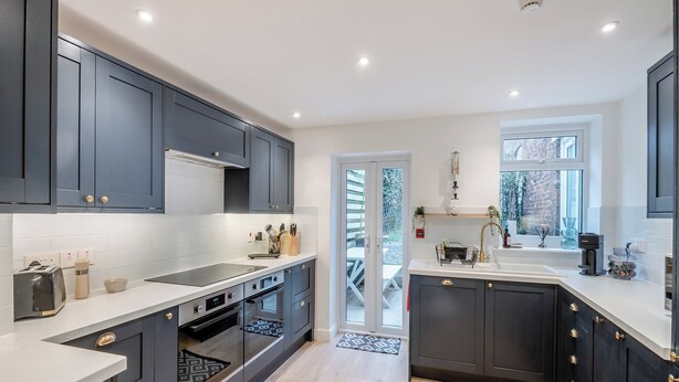 A modern kitchen with dark cabinets, a white countertop, and a built-in oven. - Warrington House-UK48465 (Thornton-le-Dale, near Pickering)