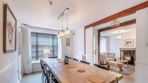 A dining area with a wooden table, chairs, pendant lights, and a view into a living room with a fireplace. - Warrington House-UK48465 (Thornton-le-Dale, near Pickering)