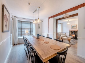 A dining area with a wooden table, chairs, pendant lights, and a view into a living room with a fireplace. - Warrington House-UK48465 (Thornton-le-Dale, near Pickering)