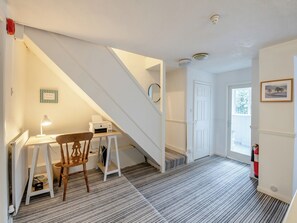 A room with a desk, chair, printer, and a staircase.