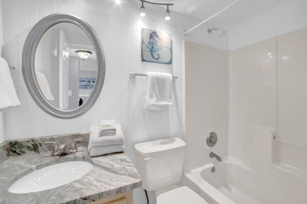 Une salle de bain moderne avec un lavabo en marbre, des toilettes, une baignoire, une douche et un miroir.