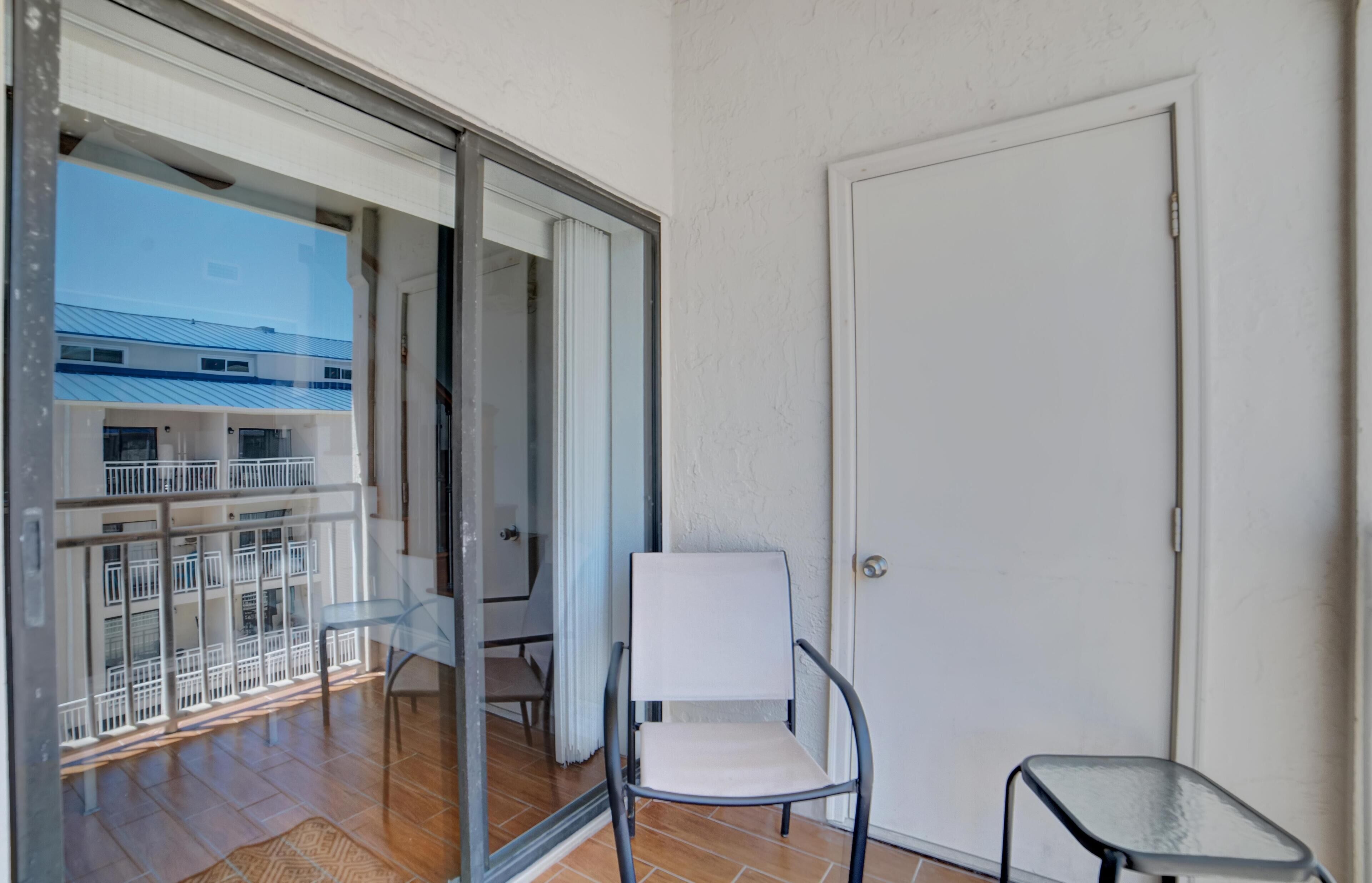 A balcony with a chair, a table, and a door.