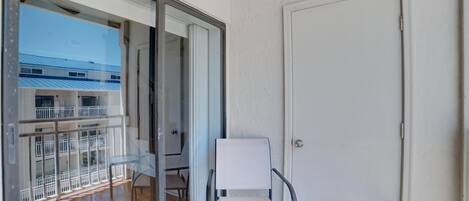 A balcony with a chair, a table, and a door.