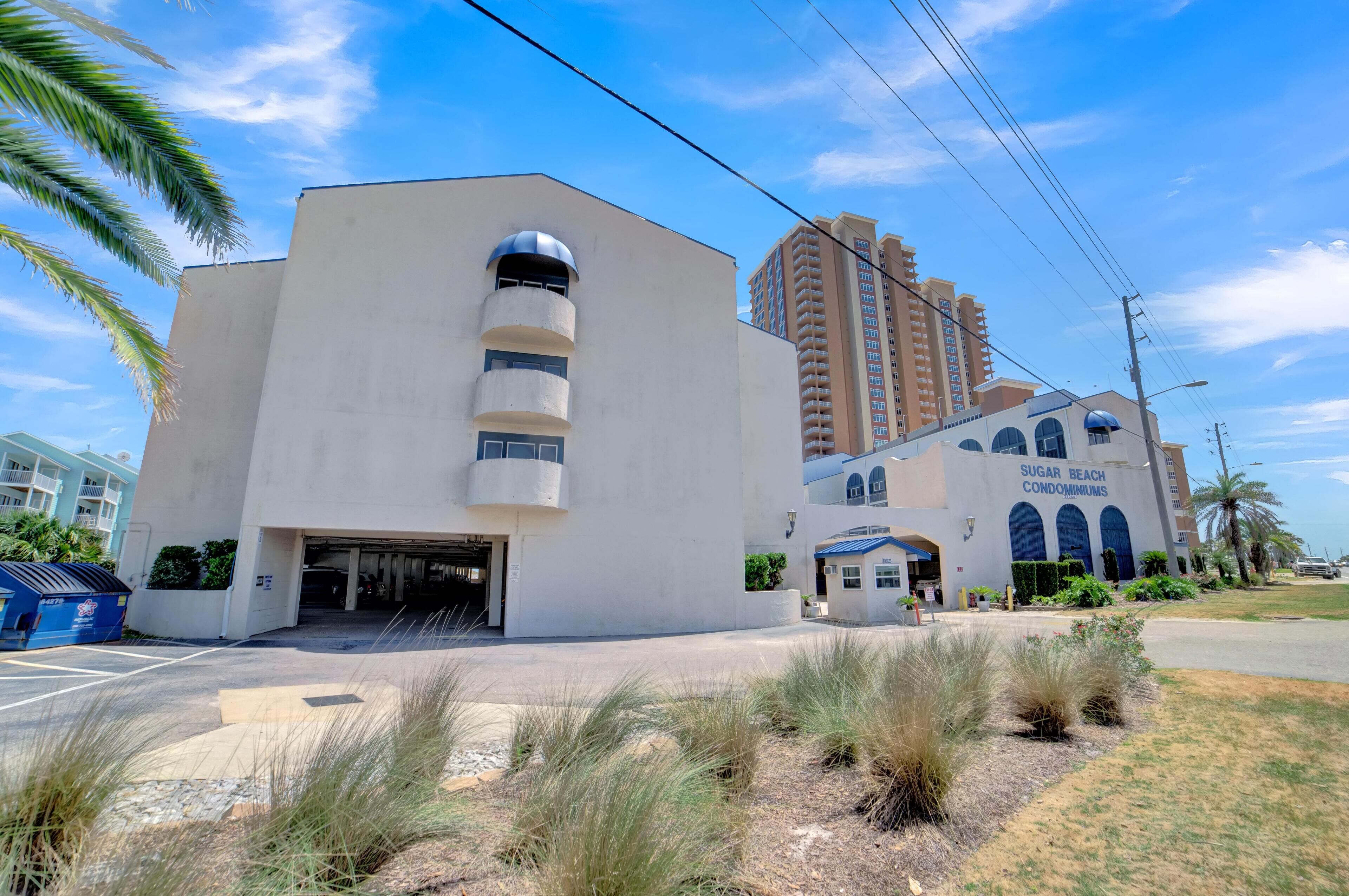 A modern building with a garage entrance, a large arched window, and a sign reading "Sugar Beach Condominiums".
