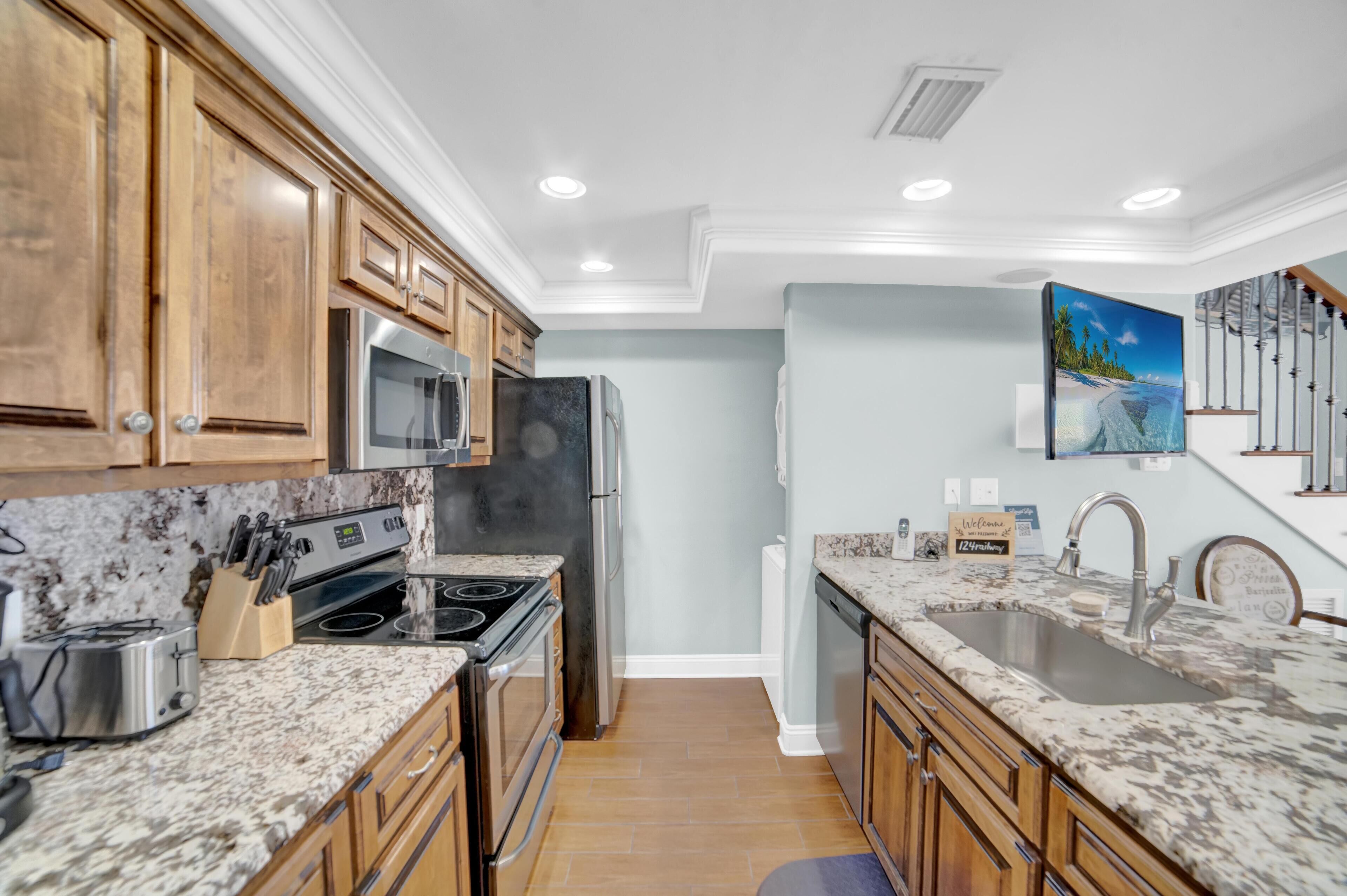 A kitchen with wooden cabinets, granite countertops, stainless steel appliances, and a painting on the wall.