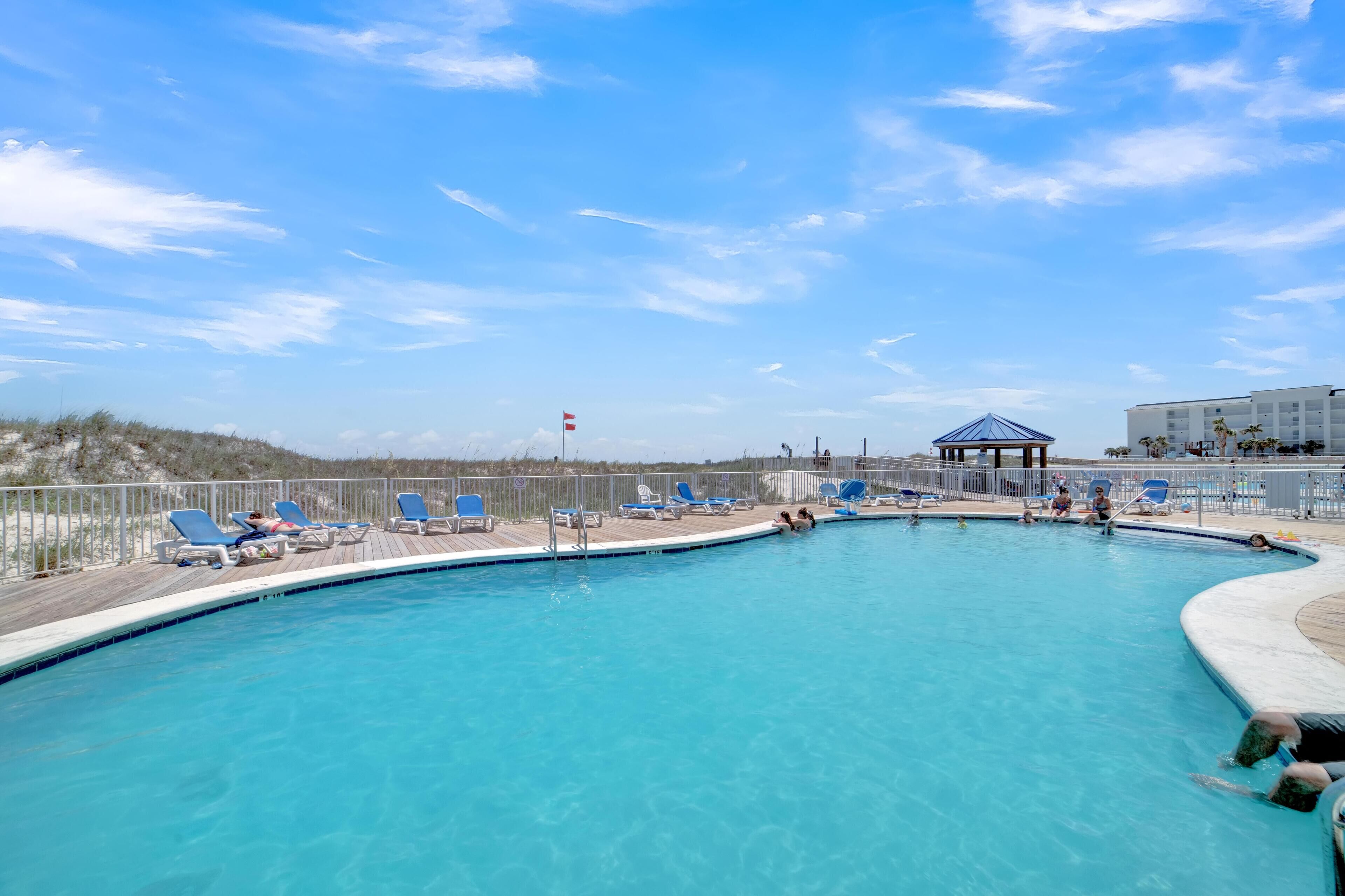 A swimming pool with blue lounge chairs and a gazebo.