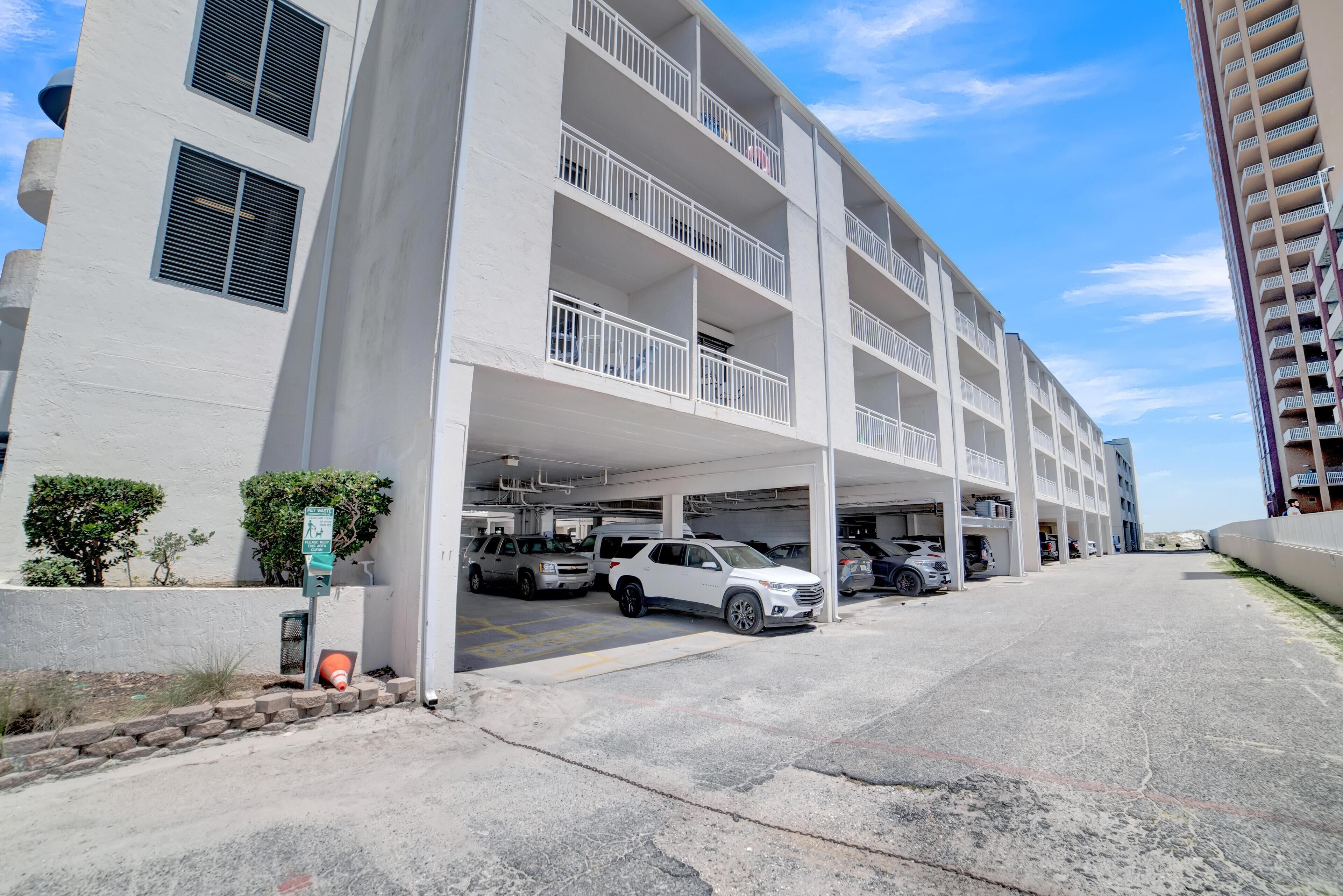 A multi-story parking garage with several cars parked, a pedestrian crossing sign, and a fire hydrant.