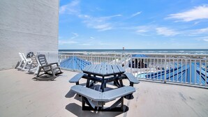 A deck with a picnic table and chairs, overlooking a beach with a clear sky. - Sugar Beach 348 (Orange Beach)