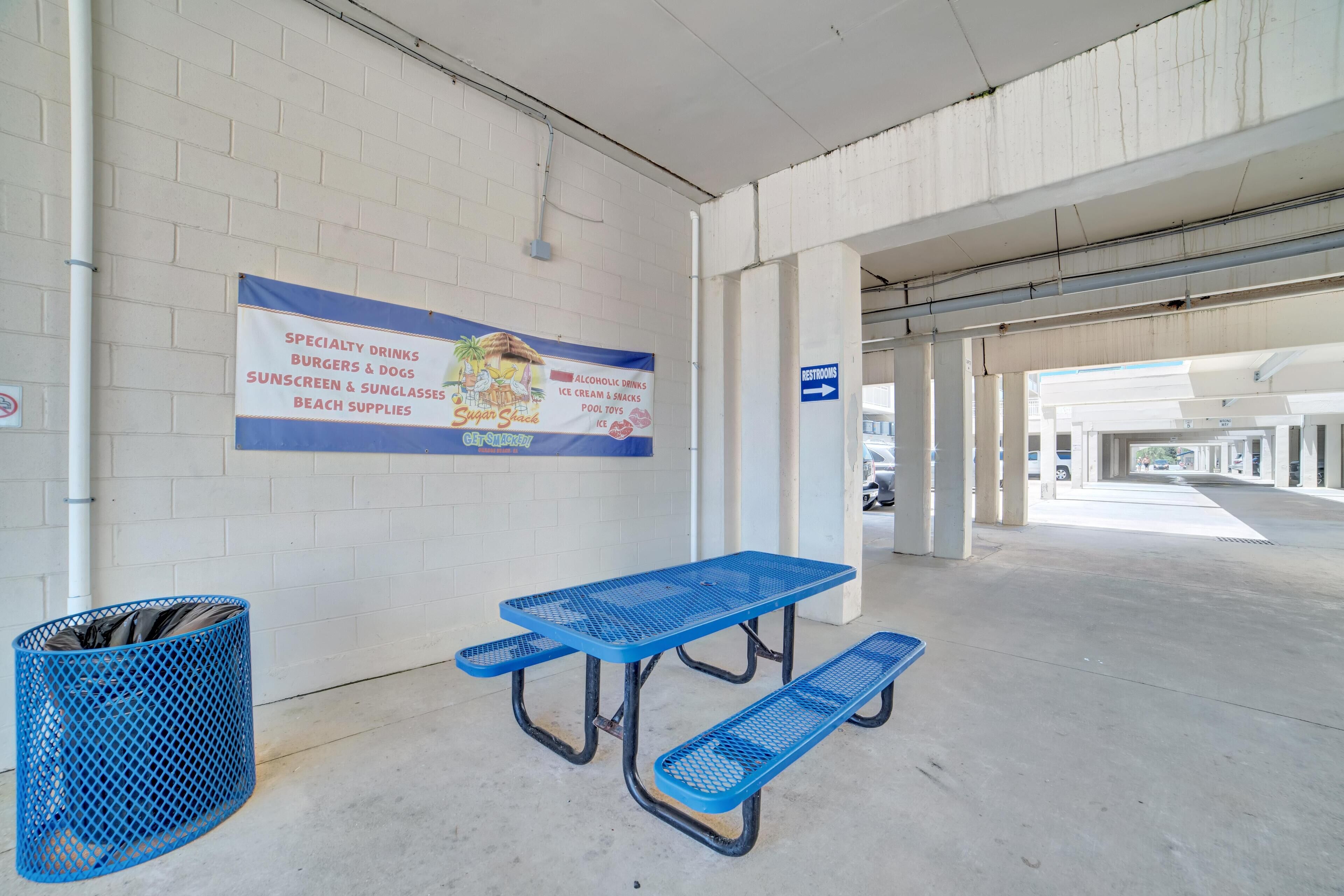 A parking garage with a picnic table and a trash bin.
