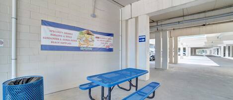 A parking garage with a picnic table and a trash bin.