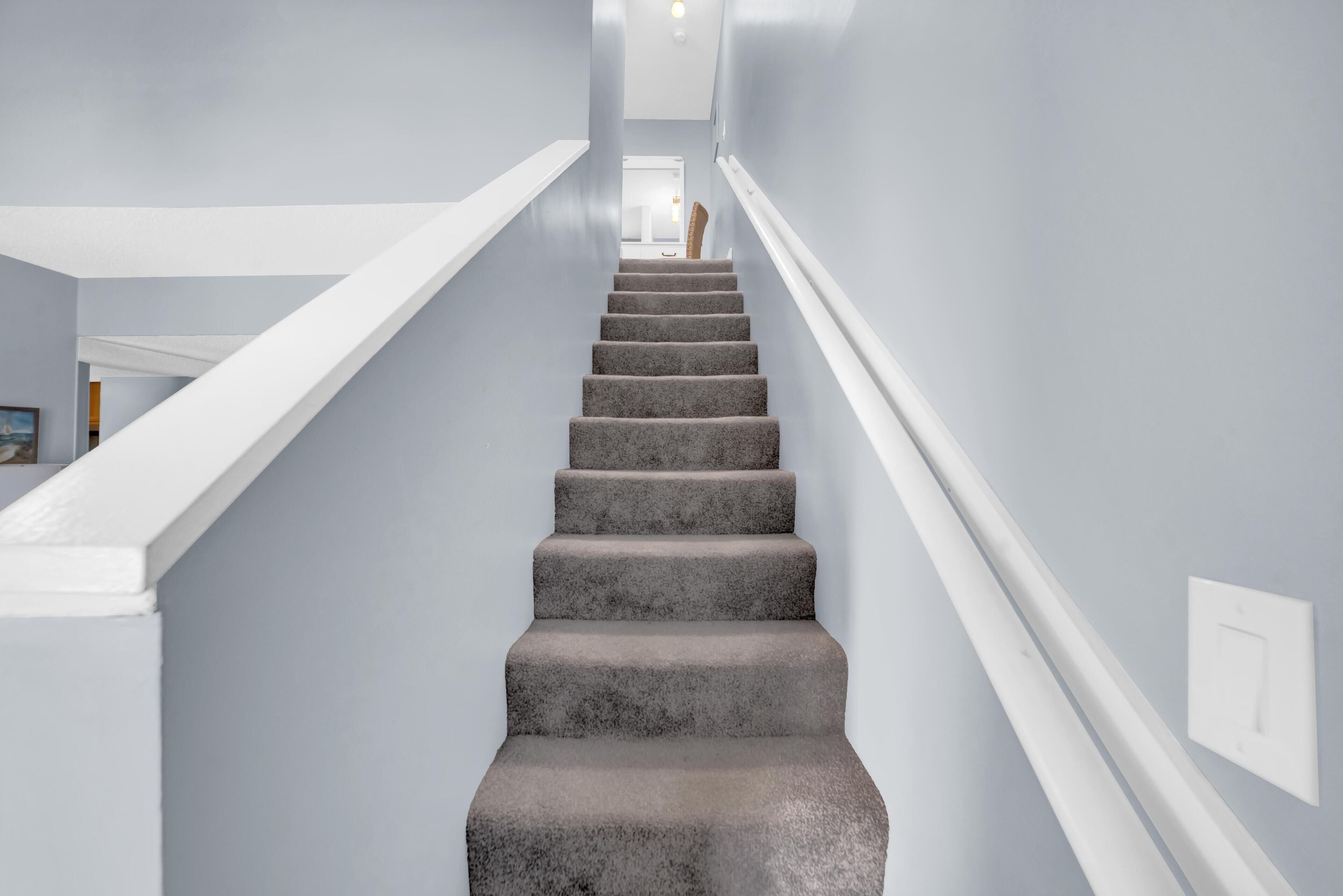 A staircase with a modern design, white railings, and a neutral wall color.