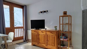 A room with a wooden cabinet, a television, a bookshelf, and a window with curtains. - Rental La Mongie Tourmalet at the foot of the slopes studio sleeps 5 (Bagnères-de-Bigorre)