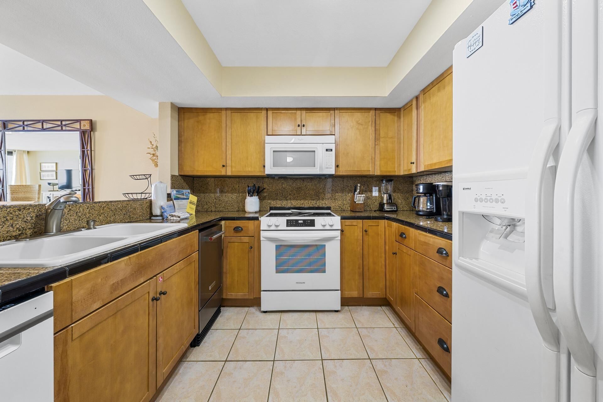 A kitchen with wooden cabinets, a microwave, a stove, a refrigerator, and a sink.