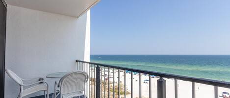 A balcony with a view of the beach and ocean.