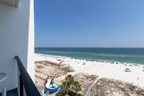 Blick auf einen Strand vom Balkon aus, mit Wasserrutsche, Sandstrand und Sonnenschirmen.