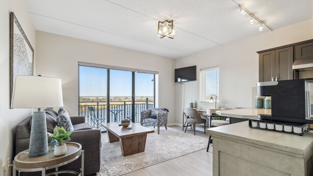 A modern living room with a sofa, coffee table, and a view of the outdoors. - Battleship Vista - Parking (Wilmington)