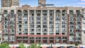 A multi-story hotel with a central courtyard, balconies on each floor, and a classic architectural design. - Battleship Vista - Parking (Wilmington)