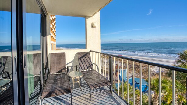 Un balcon avec vue sur l’océan, aménagé avec des chaises et une table.