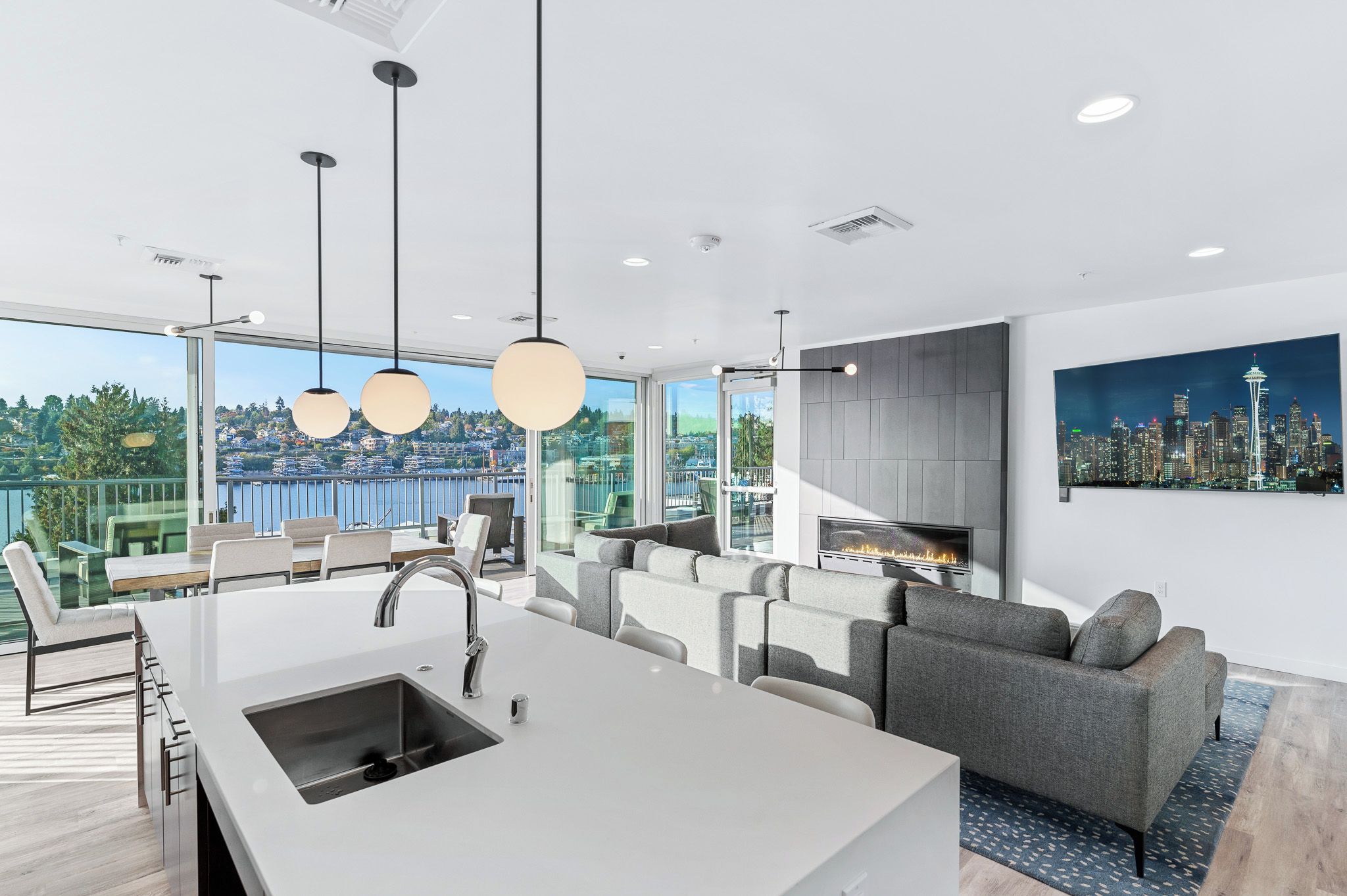 A modern kitchen with a large island, dining area with chairs, and a sofa.
