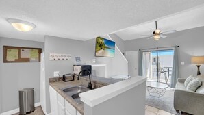 A modern kitchen with a granite countertop, stainless steel sink, and a ceiling fan. - Sugar Beach 356 (Orange Beach)